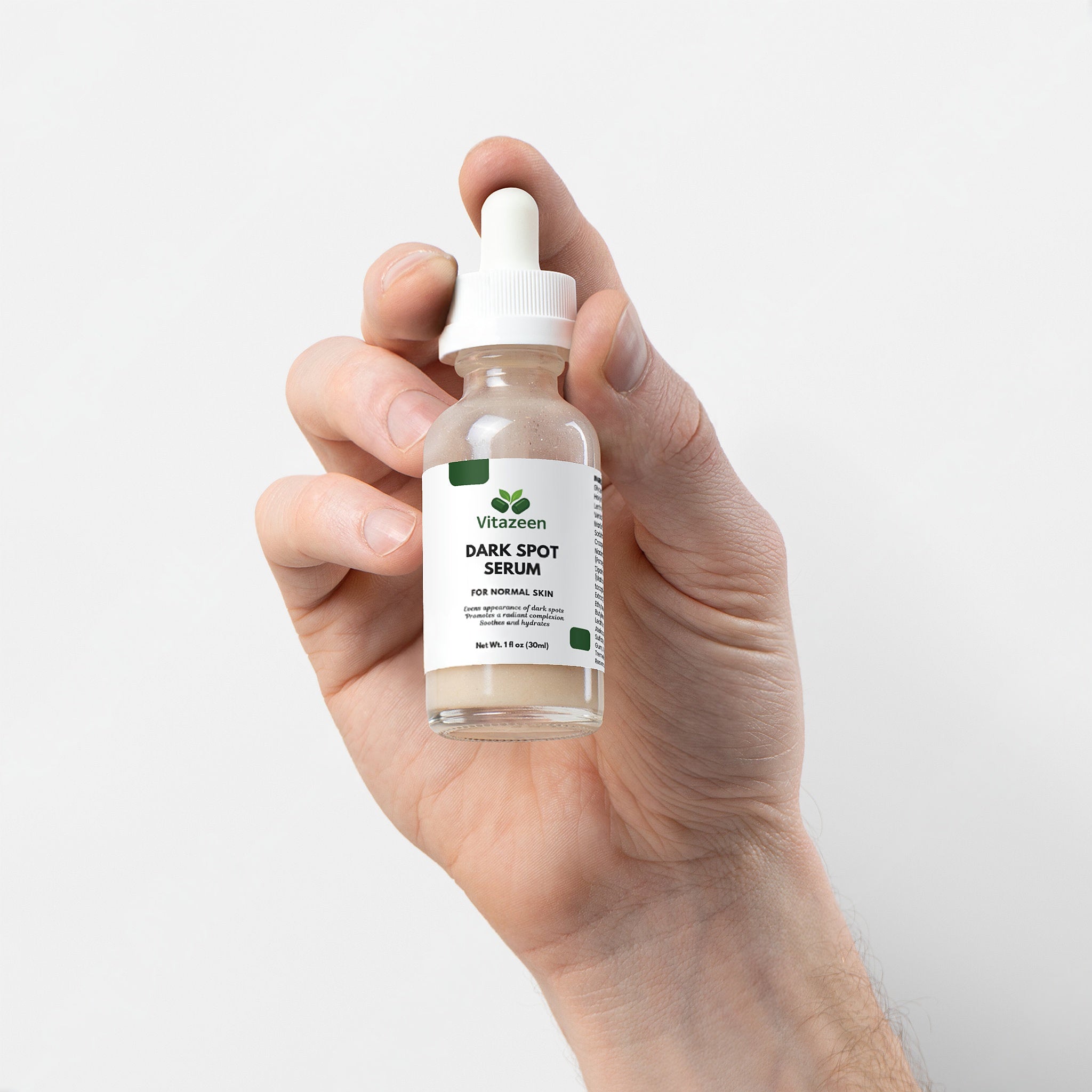 Hand holding a bottle of Vitazeen Dark Spot Serum against a white background